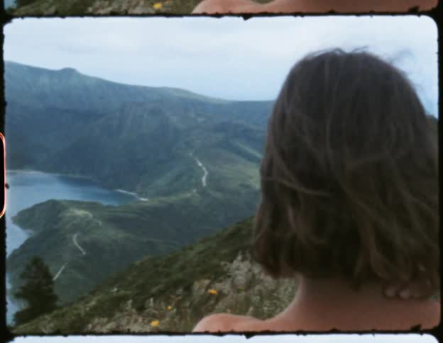 People stand on shore overlooking lake and fog covered mountain on opposite shore