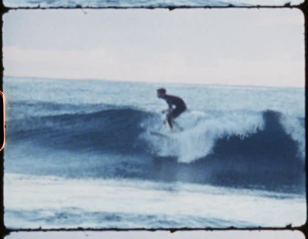 Man on a surfboard rides a wind wave in the ocean and then slips off the board