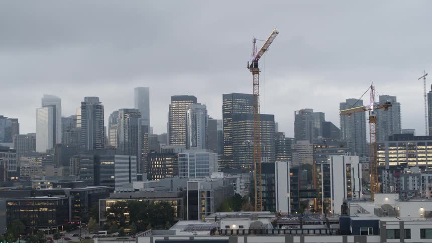 Tower cranes work above multiple new buildings under construction in a downtown city