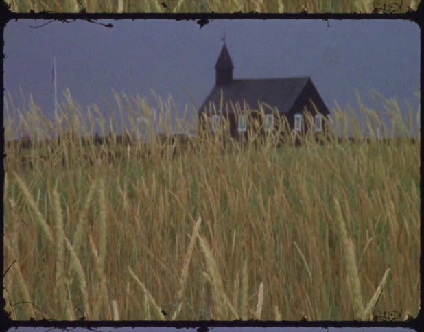 A film of a church by a field filled with wheat