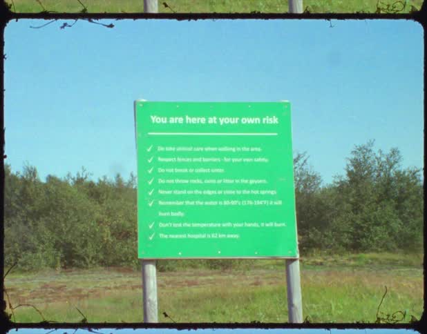 A green sign board is posted with several lines worth of warnings