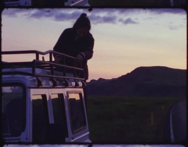 A person climbing down the roof of an all terrain vehicle at sunset