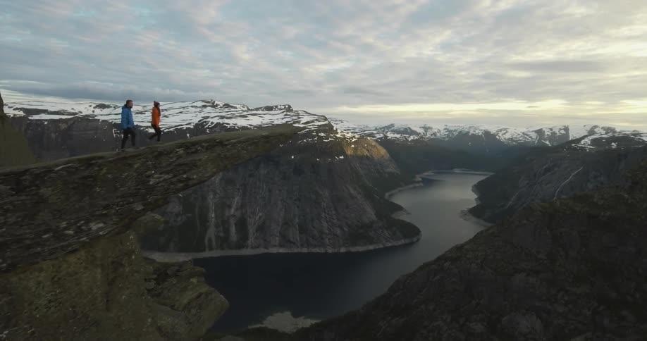 A man and women talk over to the edge of a steep cliff