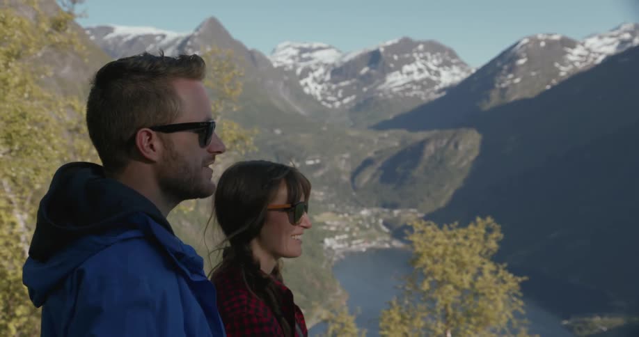 A man and woman look over a mountain range and talk