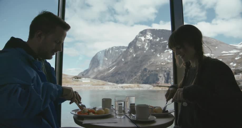 A man and women sit down to a meal by a window