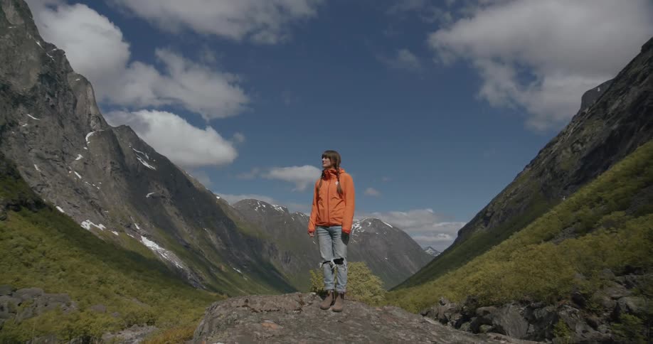 A woman stands in front of mountains