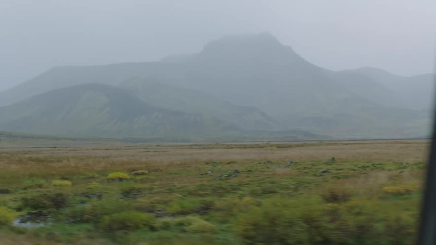Plain grasslands near to the peaks of a mountain range covered in mist