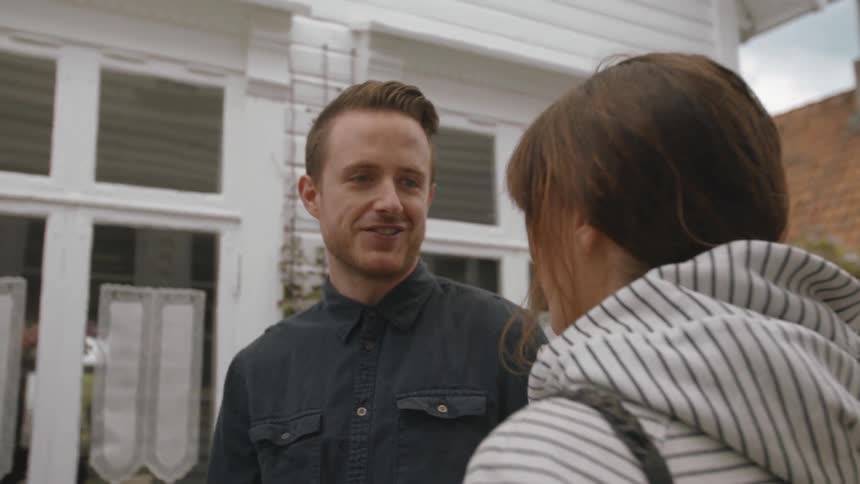 A man and women talk in front of a home