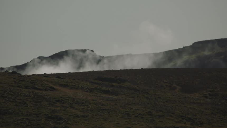 Wind blows a cloud over a hillside in the mountains