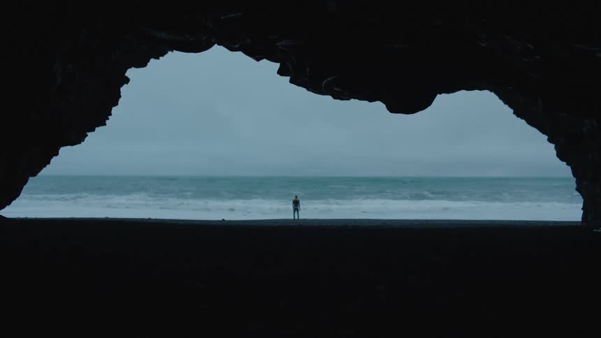 A wide shot of a person walking towards an ocean