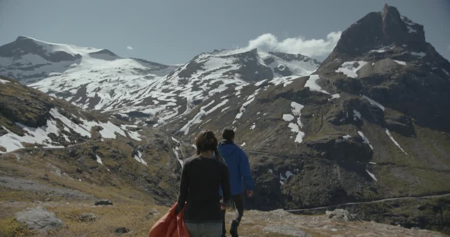 A man and woman walk down a rocky slope