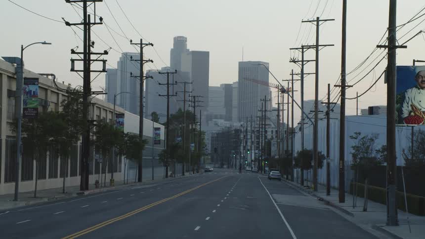 A road leading towards skyscrapers looming over the city during the day