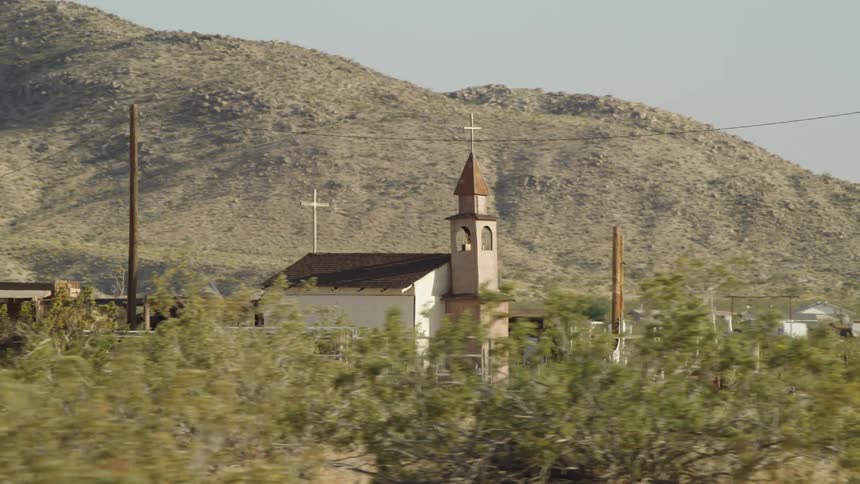 A small chapel below surrounding by a fence in the countryside during the day
