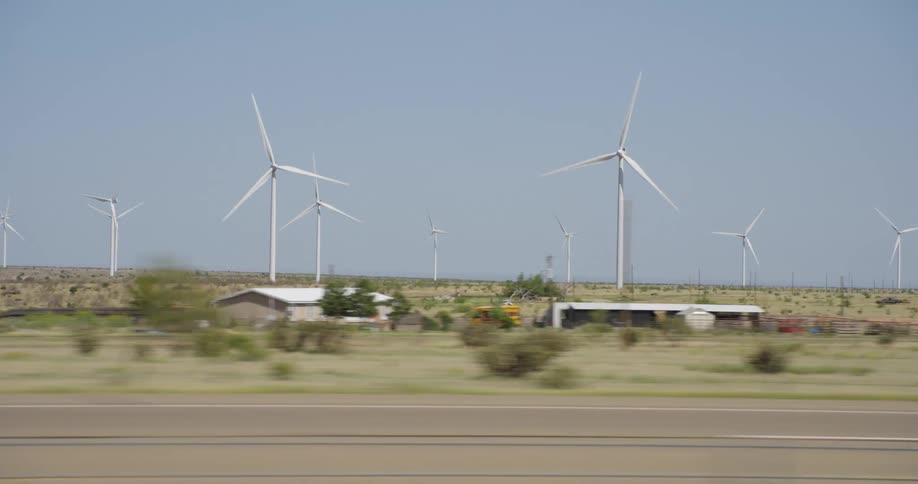 Shipping trucks driving past a wind farm