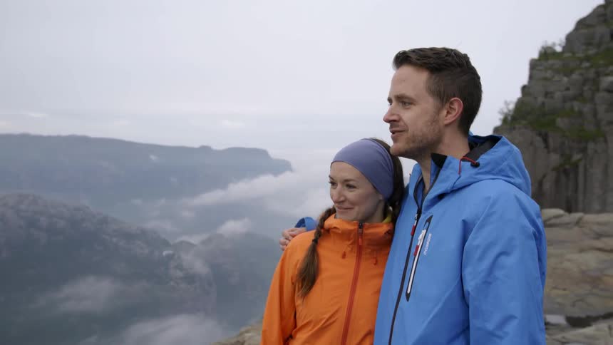 A man and woman smile as they look out over a cliff