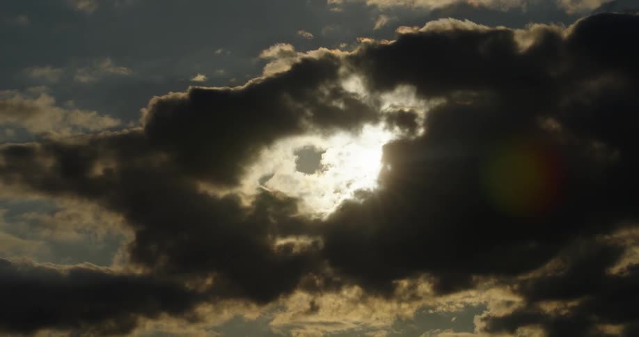A shot zooming out of a sunset behind the clouds