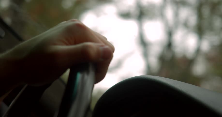 A mans hand on a steering wheel as he drives a car
