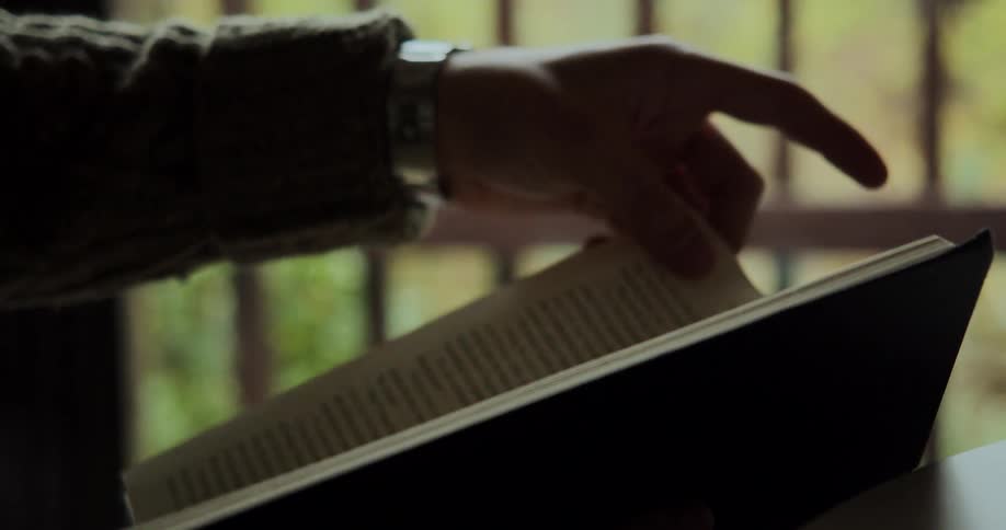 Hand turning the page of a hard cover book