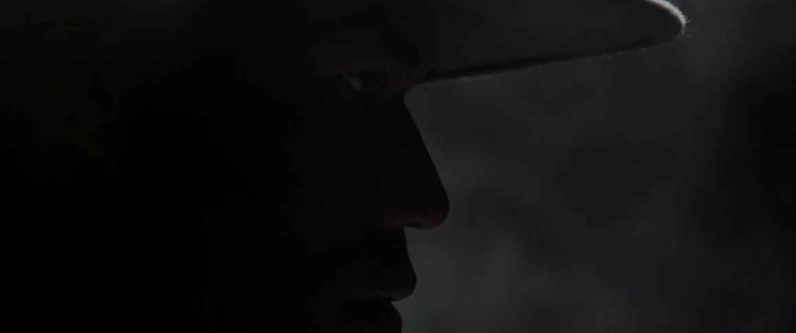 A man wearing a hat with smoke in the background