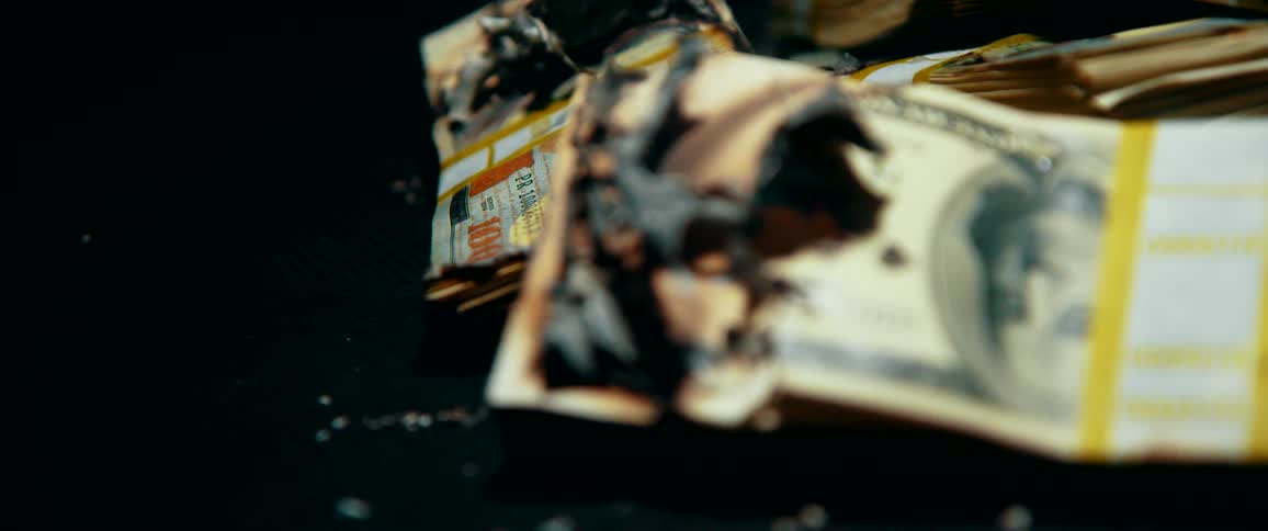Money with a hold burnt in it and smoke rising from it