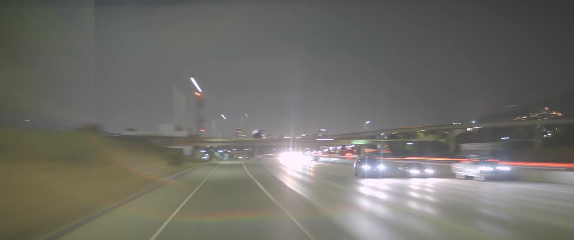 Time lapse of a vehicle traveling at night on streets and highways with lots of traffic in a hilly region