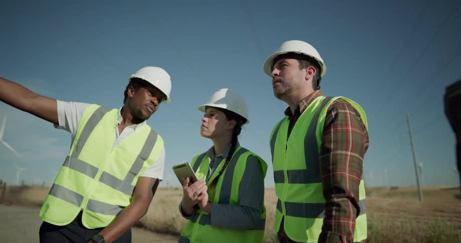 Three construction worker employees are standing in a rural area