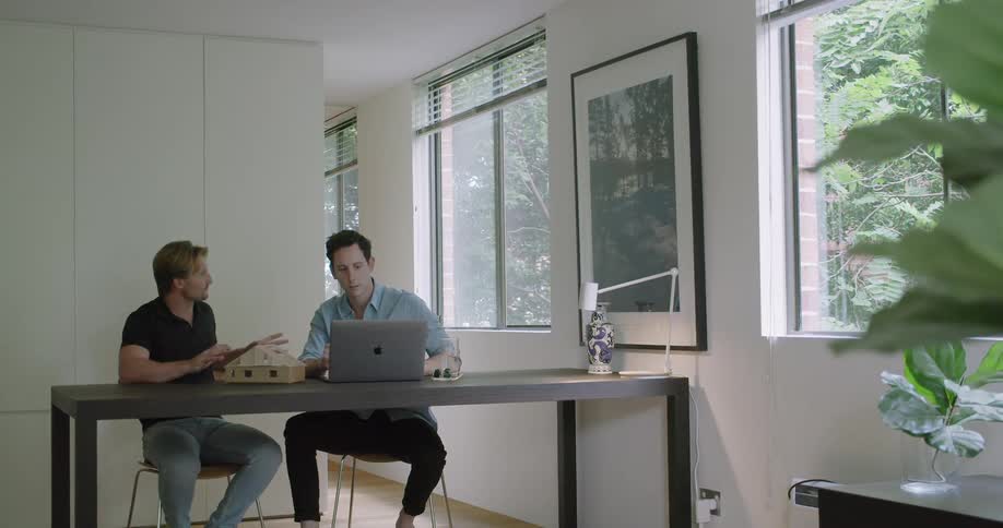 Two men are working together by a laptop
