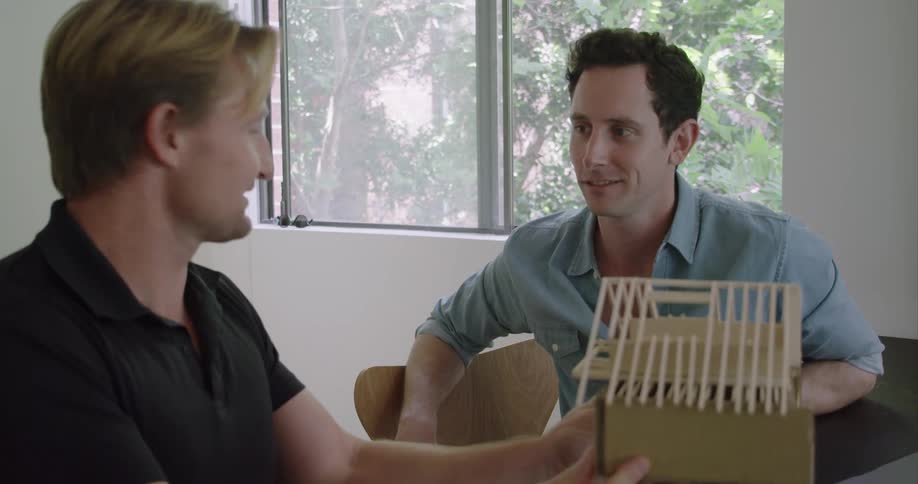 Two men talk and examine a model house