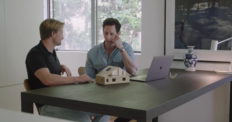 Architect talking to a customer in front of a scale balsa wood model of a house at the office