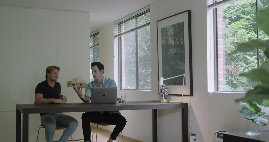 Two coworkers sit at a desk and look at a model of a building