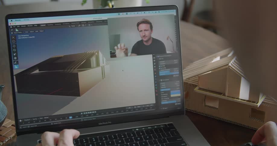 A person communicates with his boss on his laptop discussing a house design while sitting at a table at home