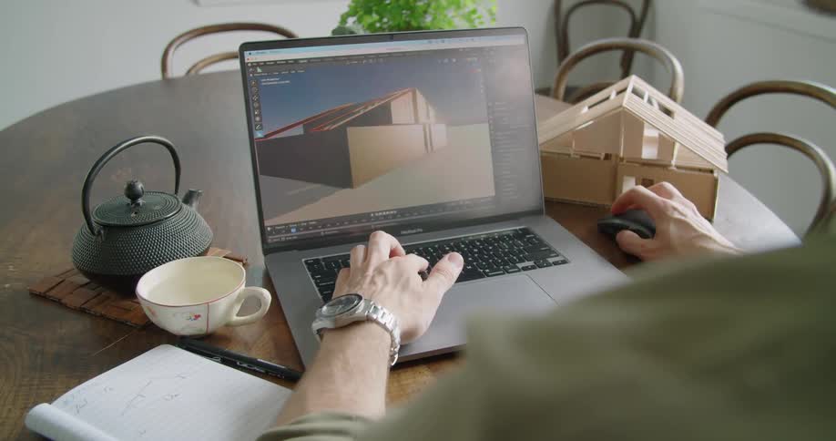 Architect drawing a computer model of a house based on a real balsa wood scale model