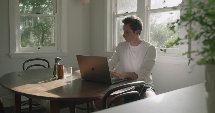 A man working on a computer before answering a cell phone