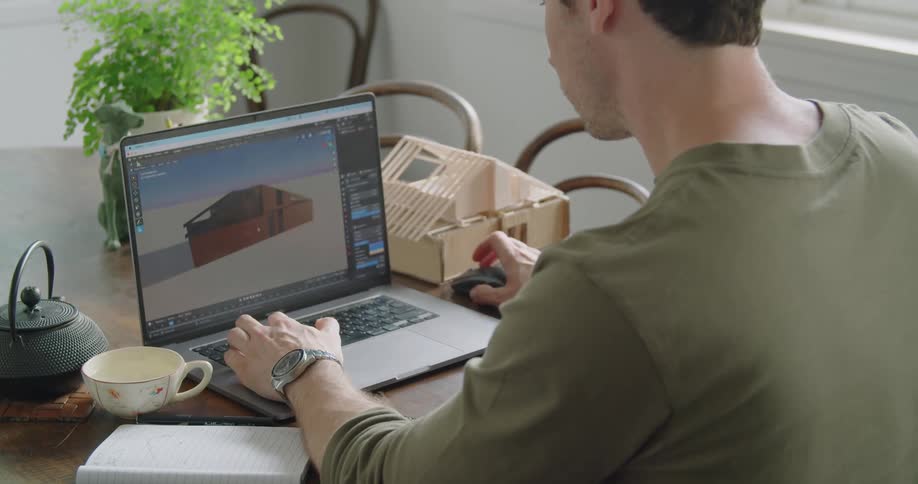 A man sitting in a room by a table using a laptop