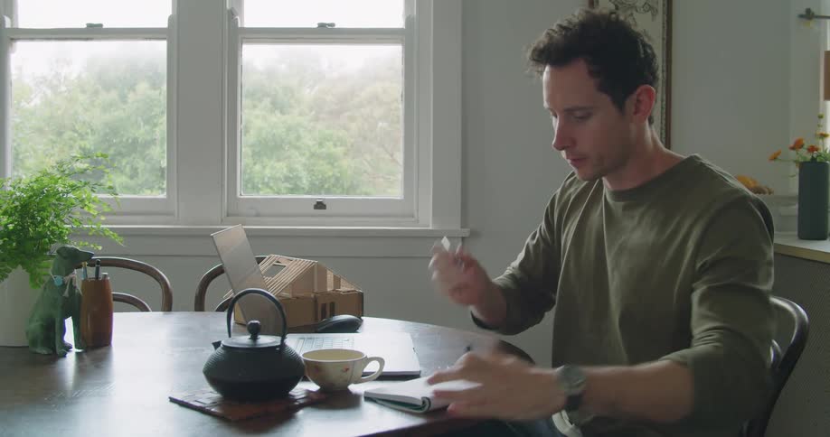 A man drinking tea while working from home on his laptop