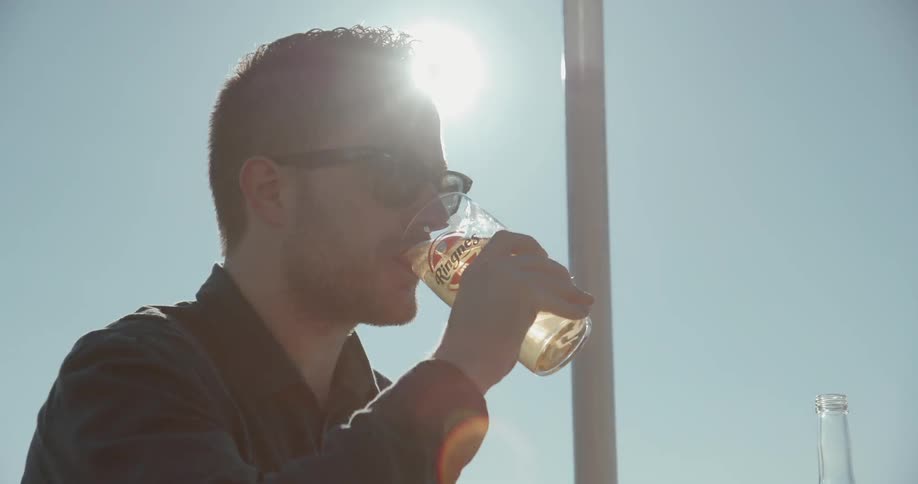 A man drinks from a glass on a sunny day
