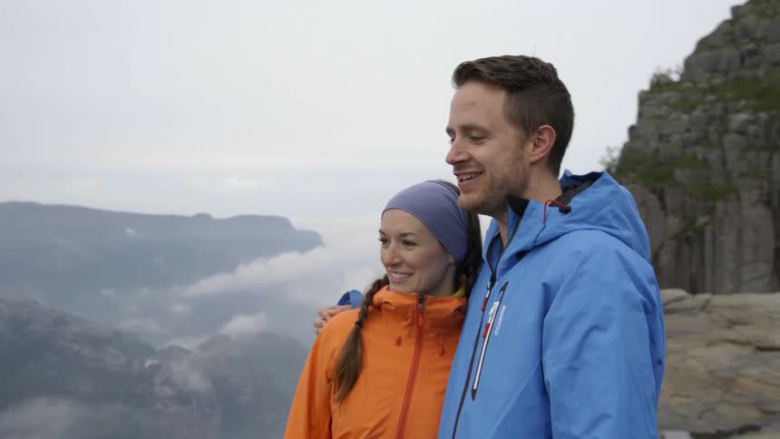 A man and woman smile on a mountain