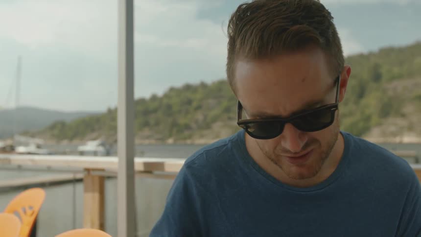 A man wearing glasses sits outside