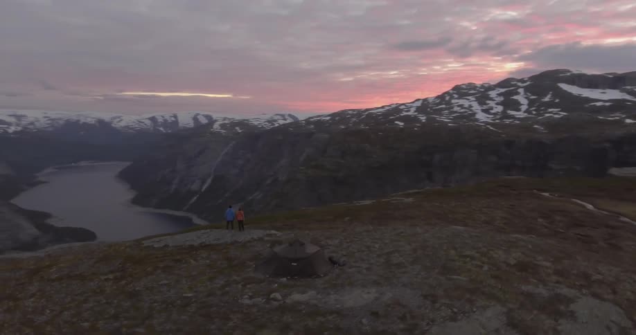 Two people enjoying the view of snow capped mountains after sunset