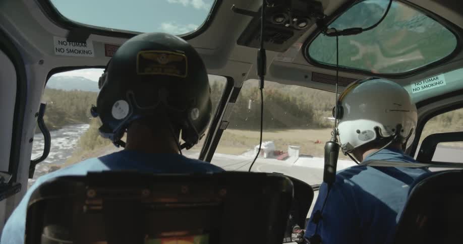 Two people are sitting in a helicopter as it takes off