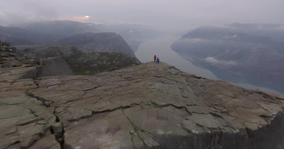 Aerial view of people standing at the edge of a mountain cliff