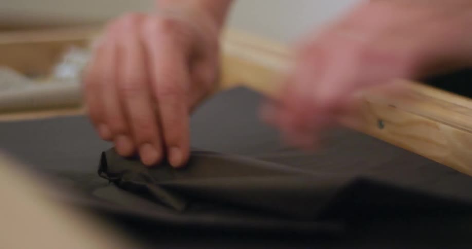 A person with a ring putting a bowl on black paper and wrapping it