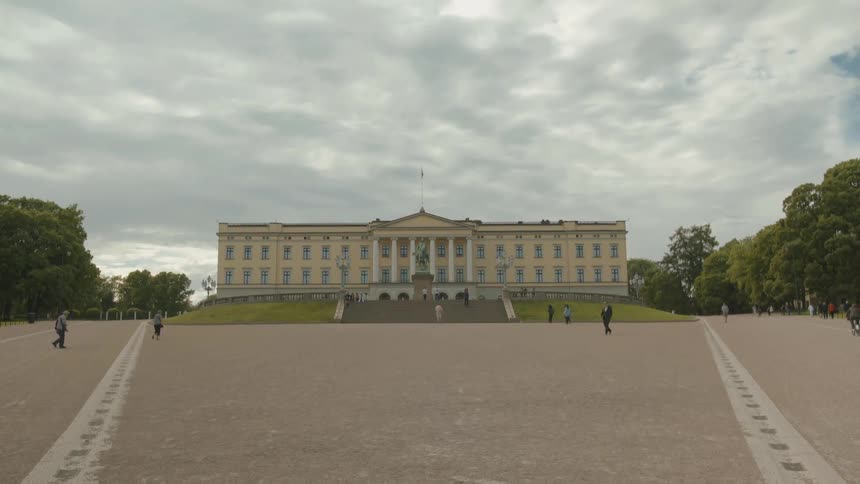 People are walking along a square before a building