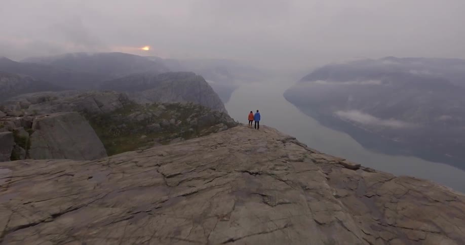 Aerial view moving towards people on a cliffside
