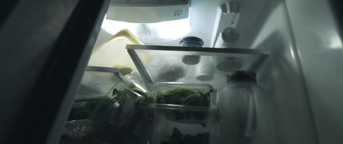 Twisting footage of an open fridge in a dark room