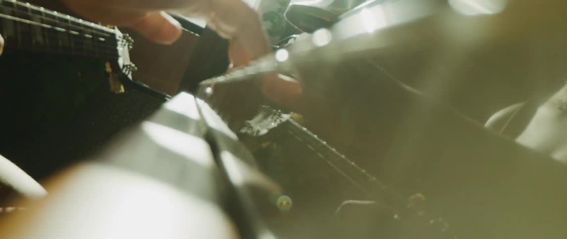 A musician holds a guitar and taps keys on a piano