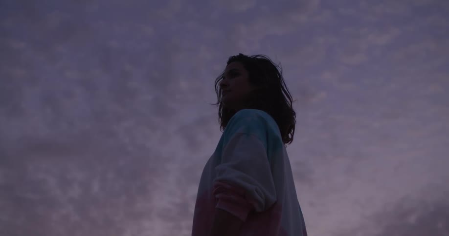 A woman is standing under a cloudy sky