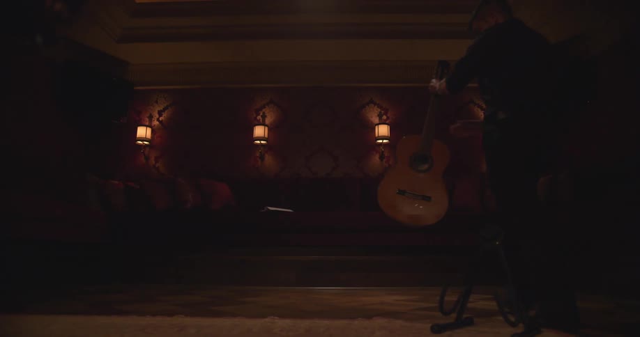 A man walks on stage and picks up a guitar from a stand