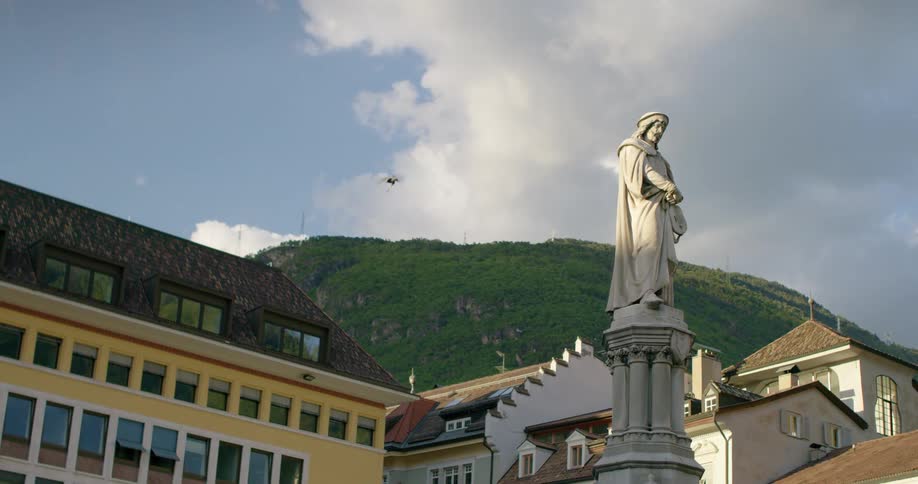 A bird flies past the statue of a man