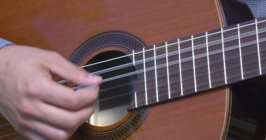 A man strums the guitar with his fingers